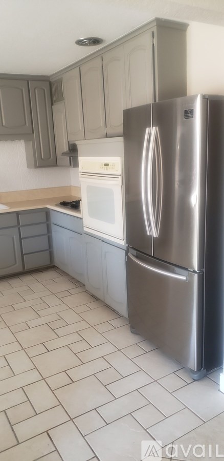 A kitchen with a refrigerator, oven, and cabinets.