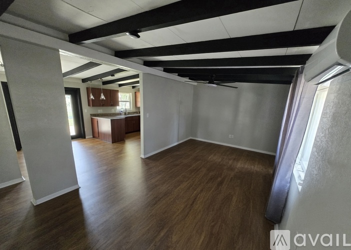 A spacious room with wooden flooring and white walls.