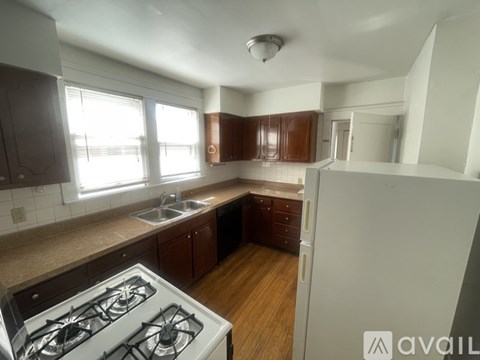 A kitchen with a white stove and wooden floors.