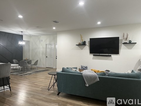 A living room with a grey couch and a television on the wall.