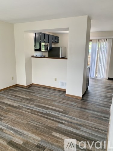 A room with wooden flooring and a kitchenette with a microwave and oven.