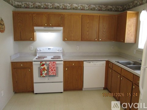 A kitchen with wooden cabinets and a white stove top oven.