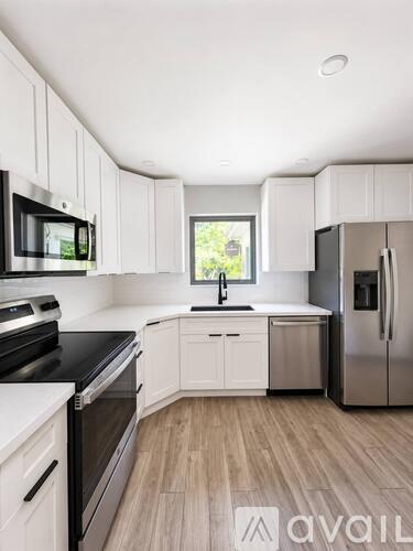 A modern kitchen with white cabinets and stainless steel appliances.