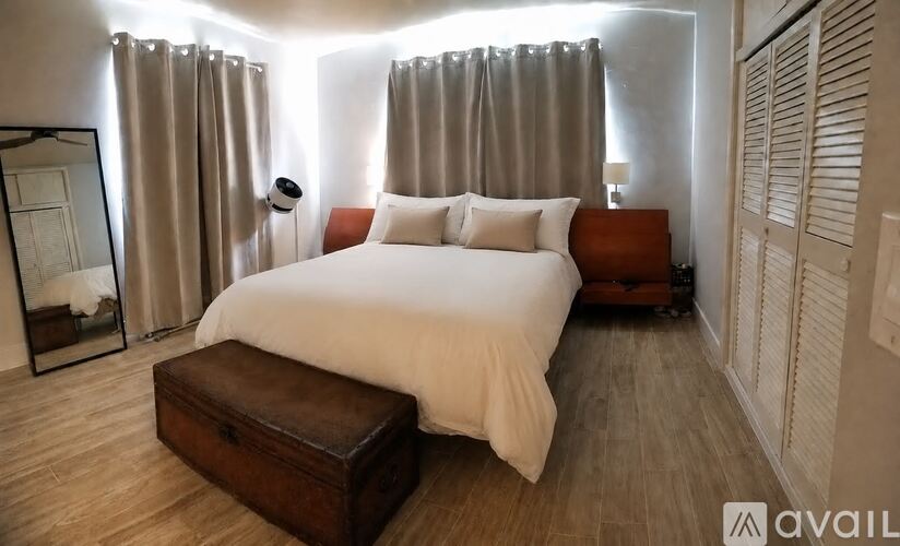 A bedroom with a large bed and a wooden bench.