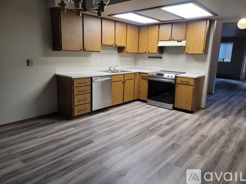 A kitchen with wooden cabinets and a grey floor.