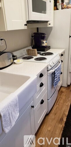 A white kitchen with a stove top oven and a microwave above it.