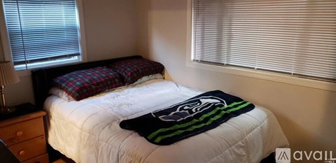 A bedroom with a bed, a blanket, and a lamp.