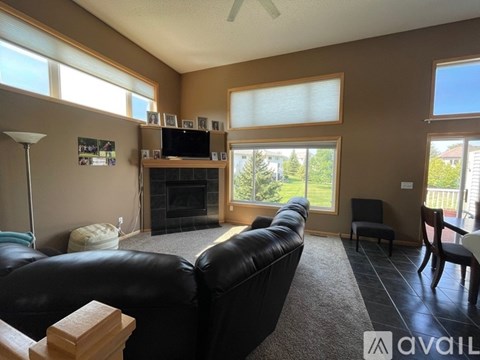 A living room with a black leather couch and a fireplace.
