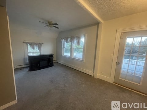 A living room with a television and a window with curtains.