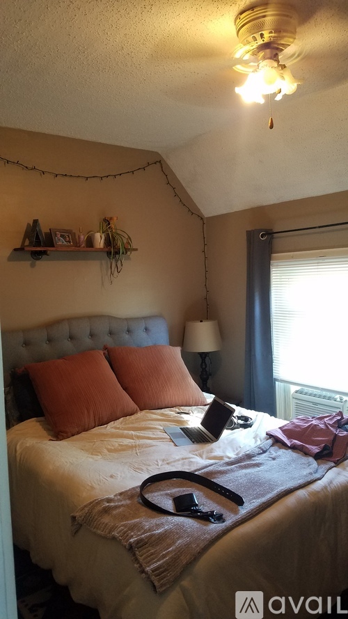 A bedroom with a bed, pillows, and a lamp.