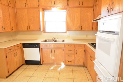 A kitchen with wooden cabinets and a white dishwasher.