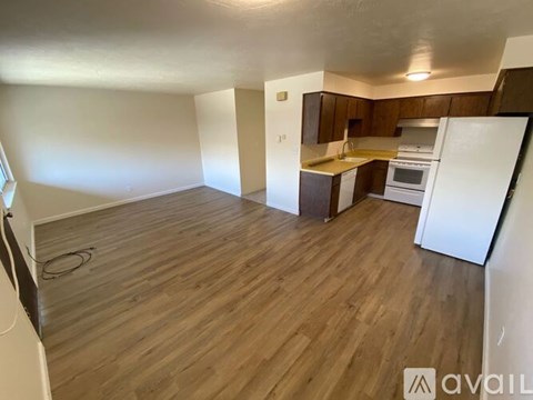 A kitchen area with a white refrigerator and wooden flooring.