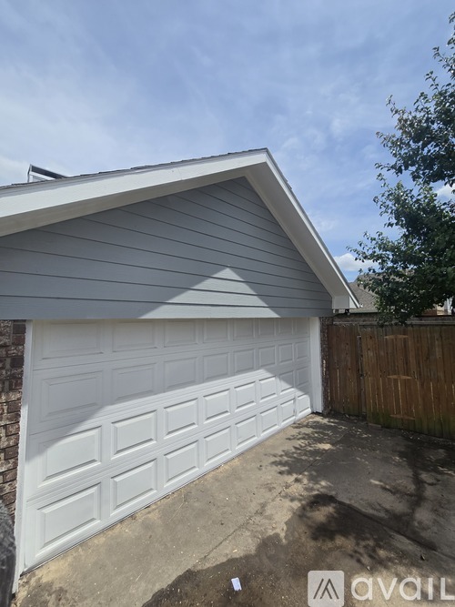 A white garage door is closed and the wall is brick.
