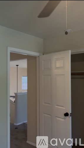 A white door with a black handle is in a room with a ceiling fan.