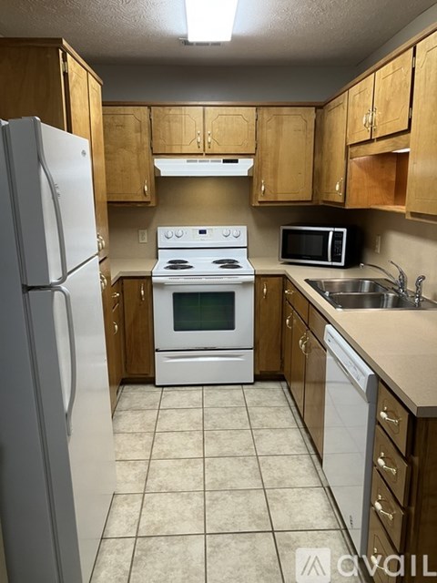 A kitchen with a white refrigerator, white stove, and a white microwave.