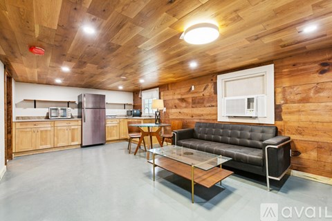 A modern kitchen with wooden walls and a black leather couch.