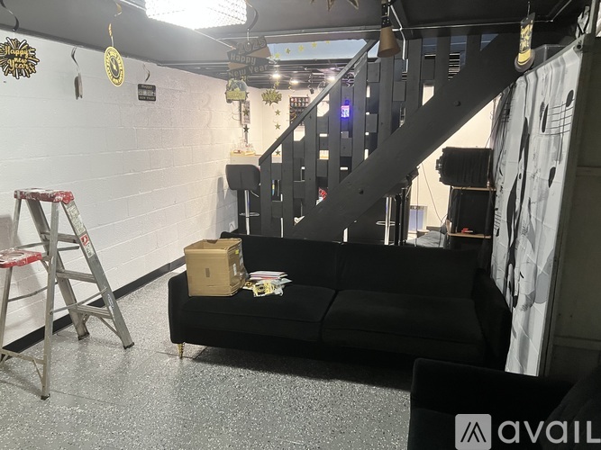 A room with a black couch and a ladder.