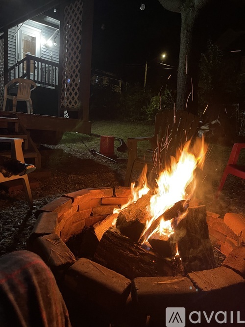 A fire burns in a brick fire pit on a porch.