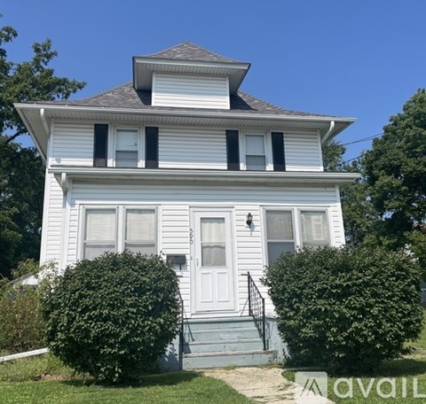 A white house with a black roof and a small porch.
