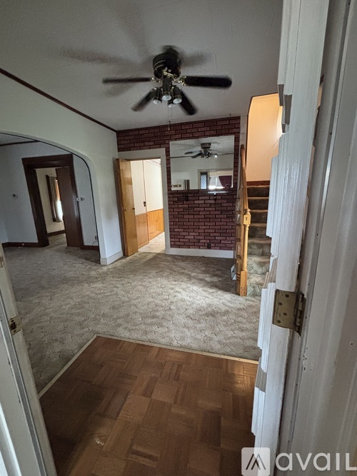 A room with a ceiling fan and a brick wall.