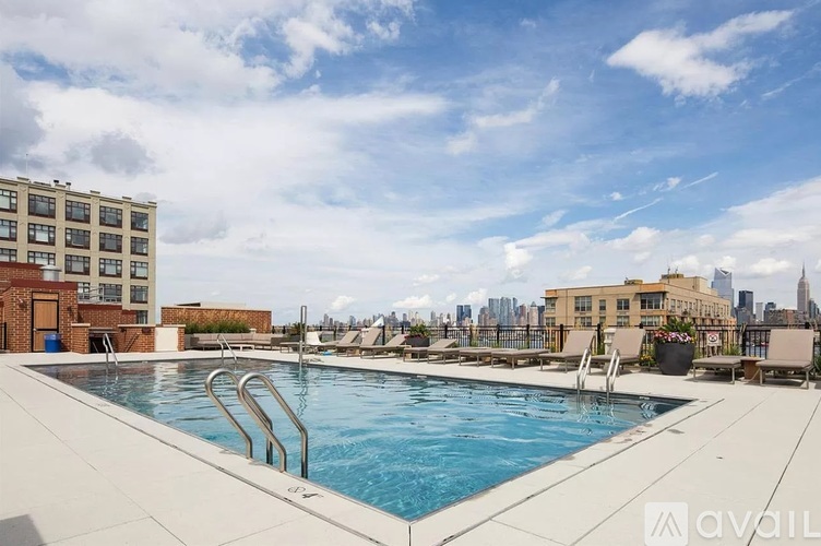 A swimming pool on a rooftop with a city skyline in the background.