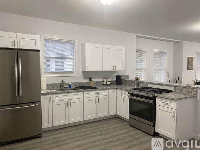 A kitchen with white cabinets and a stainless steel refrigerator.