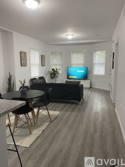 A living room with a black couch and a television displaying the word "Roku".