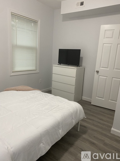 A bedroom with a bed, dresser, and television.