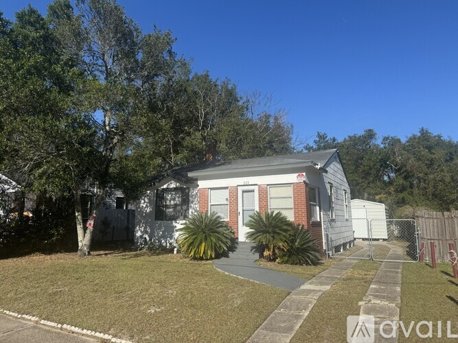 A house with a white fence and a tree in front of it.