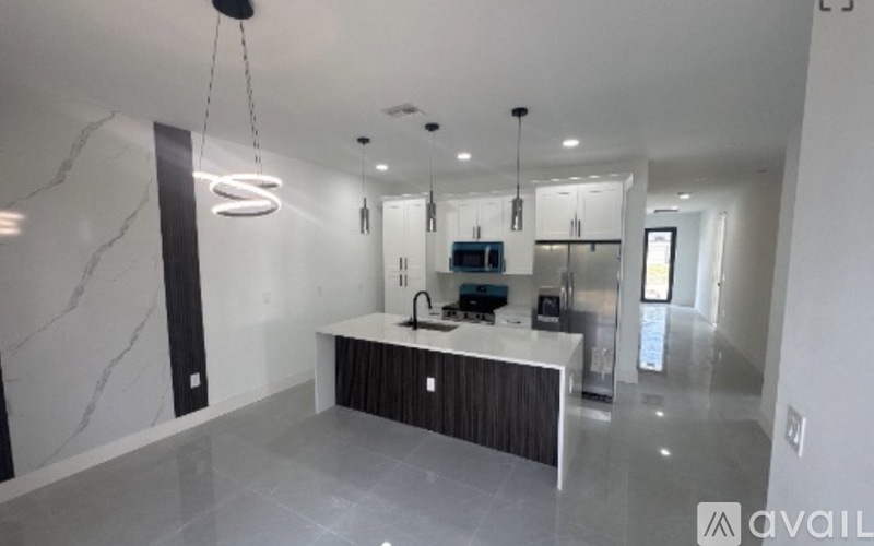 A modern kitchen with a marble countertop and a hanging light fixture.