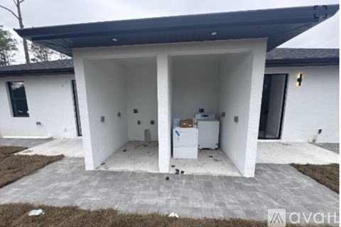 A white house with a black roof and a white refrigerator in the kitchen.