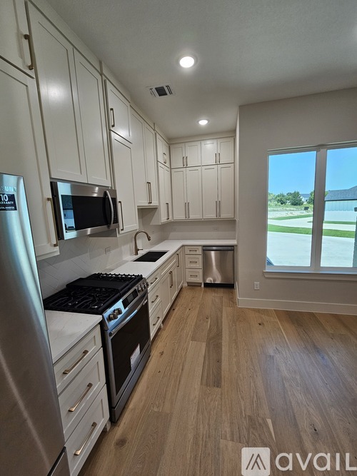A kitchen with white cabinets and a stainless steel refrigerator.