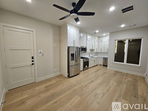A kitchen with white cabinets and a wooden floor.