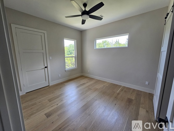 A room with a ceiling fan and two windows.