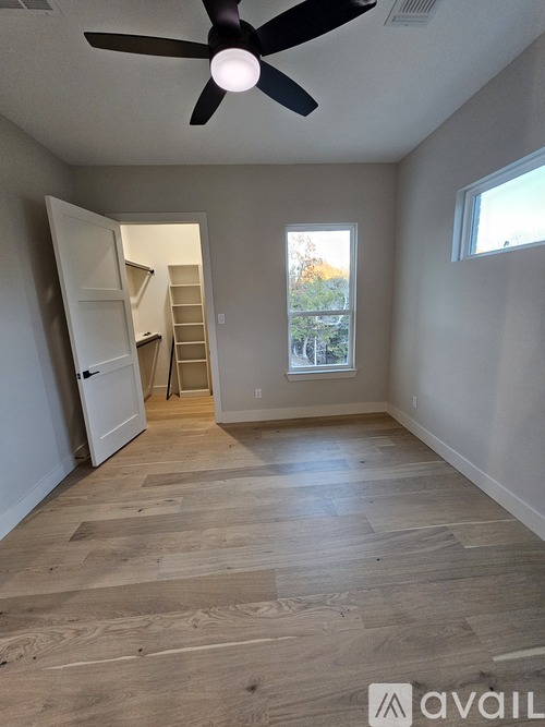 A room with a ceiling fan and wooden flooring.