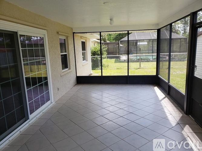 A patio with a black fence and a tennis court in the background.