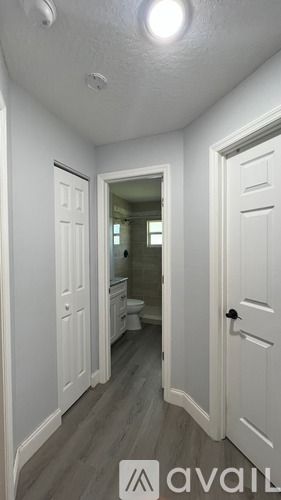 A hallway with a door on the right and a mirror on the wall.