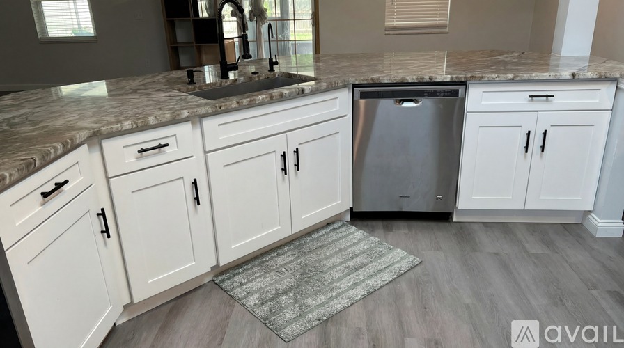 A kitchen with white cabinets and a granite countertop.