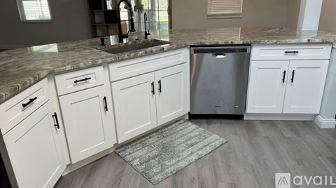 A kitchen with white cabinets and a granite countertop.