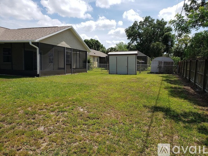 A grassy yard with a building and a fence.