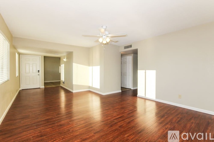 A spacious room with wooden floors and a ceiling fan.