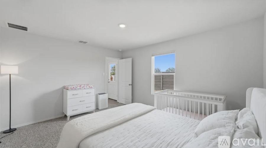 A white bedroom with a large bed and a crib.