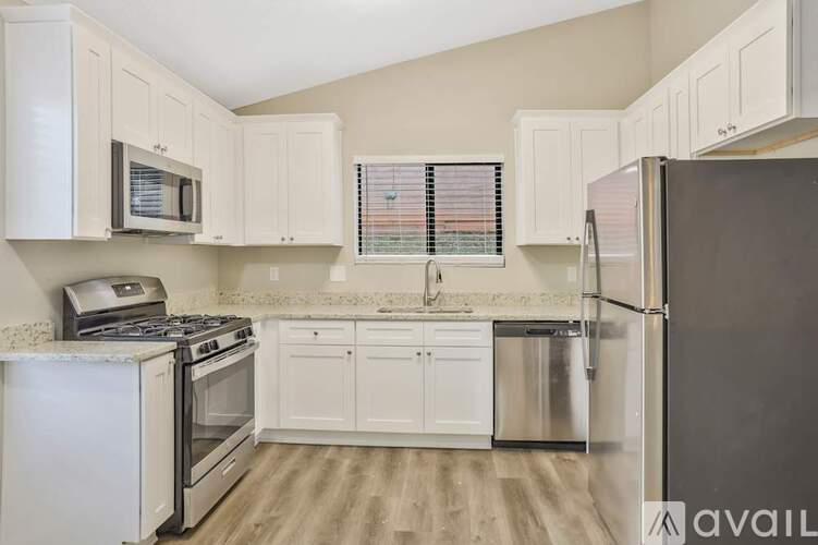 A kitchen with white cabinets and a black refrigerator.