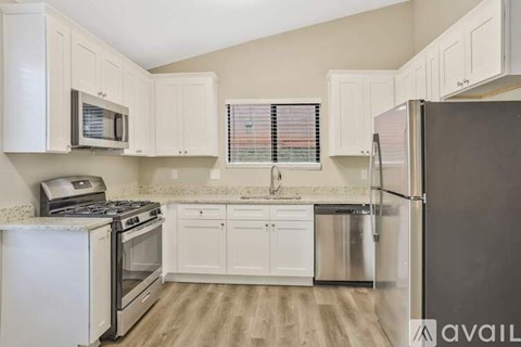 A kitchen with white cabinets and a black refrigerator.