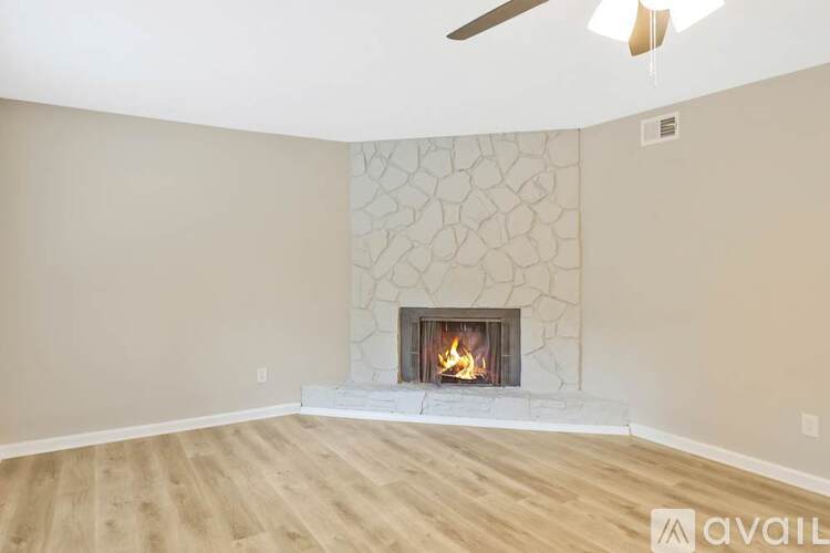 A living room with a fireplace and a fan on the ceiling.