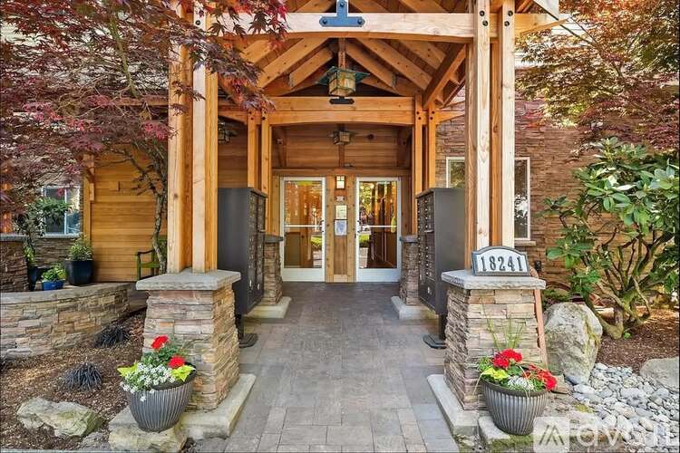 A wooden house with a porch and a stone pillar.