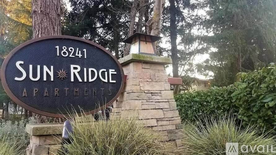 A sign for Sun Ridge Apartment is displayed in front of some trees.