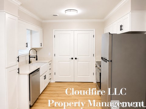 A kitchen with white cabinets and a refrigerator with Cloudfire LLC Property Management written on it.