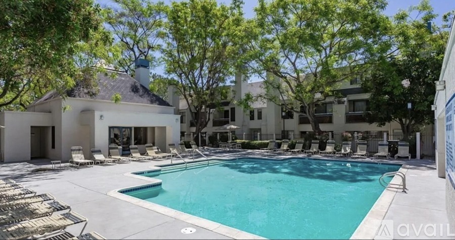 A large swimming pool surrounded by lounge chairs and trees.