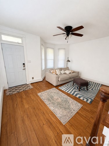 A living room with a white couch and a rug on the floor.